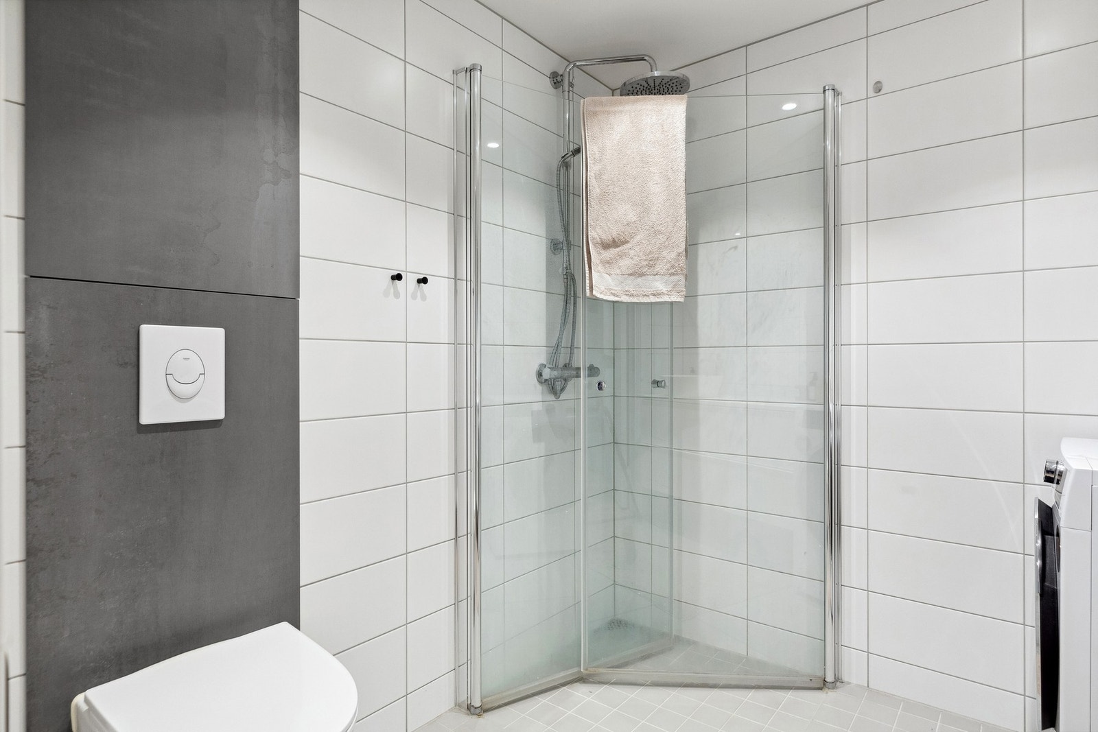 Badet har i likhet med resten av leiligheten mottatt tilstandsgrad 0 fra takstmann. Kran og avløp for vaskemaskin, dusjdører i glass, og vegghengt wc. Leilighetens rørskap befinner seg også på badet. Galleribilde