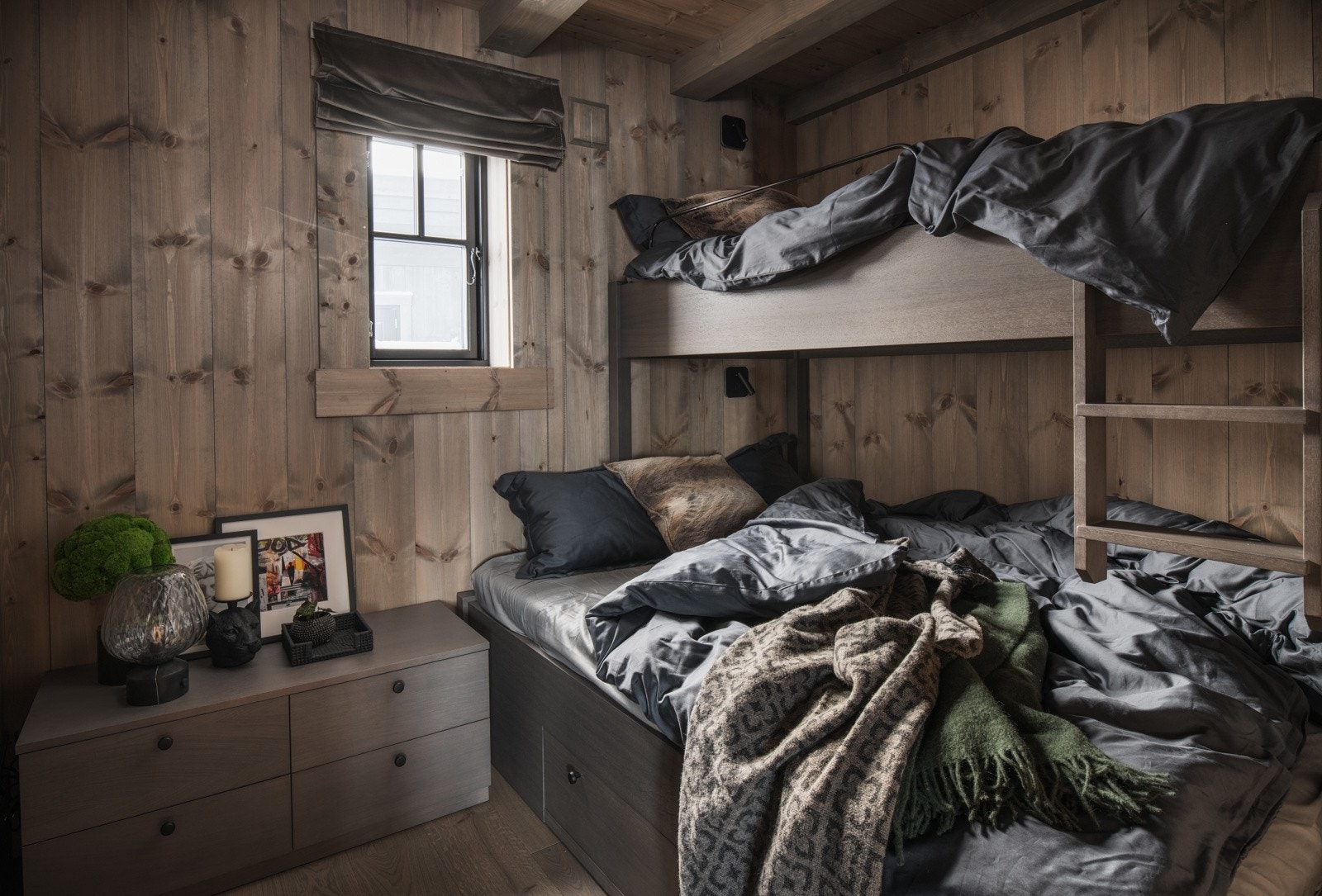 Innbydende soverom i hovedplan med snekkerbygget familiekøye med én stor skuff under, samt en kommode for oppbevaring. Galleribilde