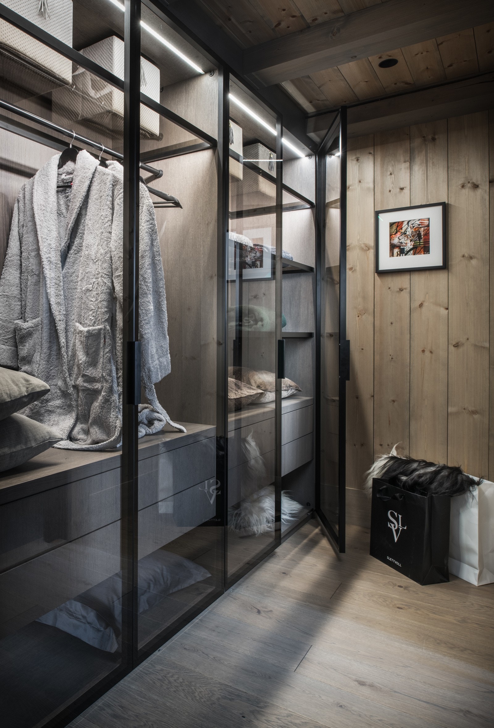 Rommet har en garderobeavdeling med glassdører og LED-belysning. Her har man rikelig med plass i både skuffer, hyller og oppheng. Galleribilde