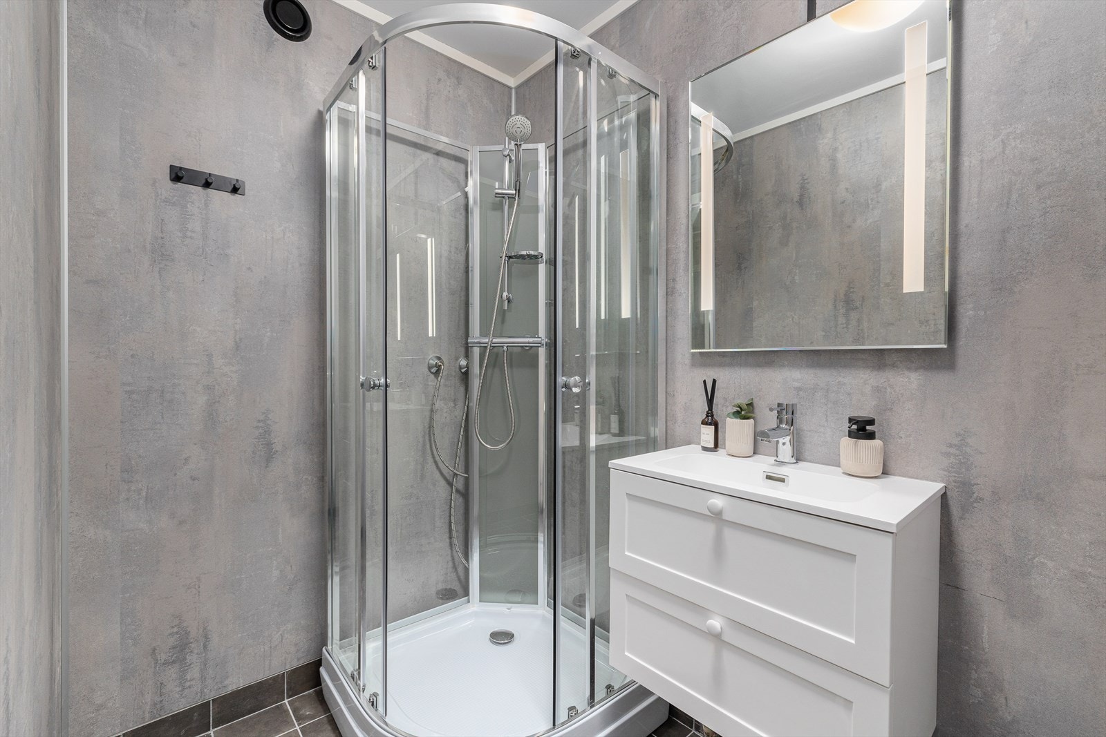 Lekkert baderom med flis på gulv med varme og baderomsplater på vegger. Galleribilde