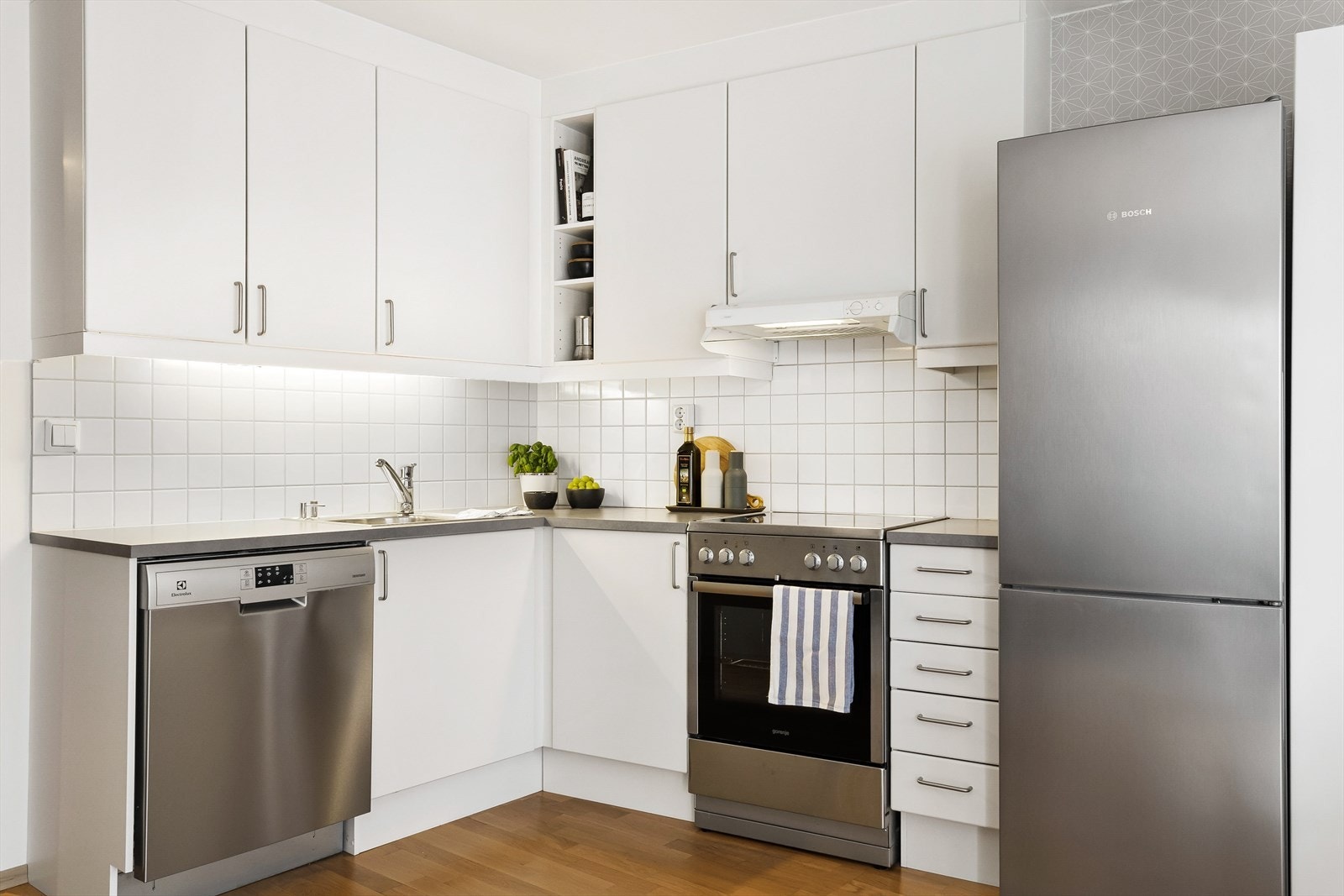 Kjøkkenet har hvite slette fronter og skap opp til taket. Galleribilde