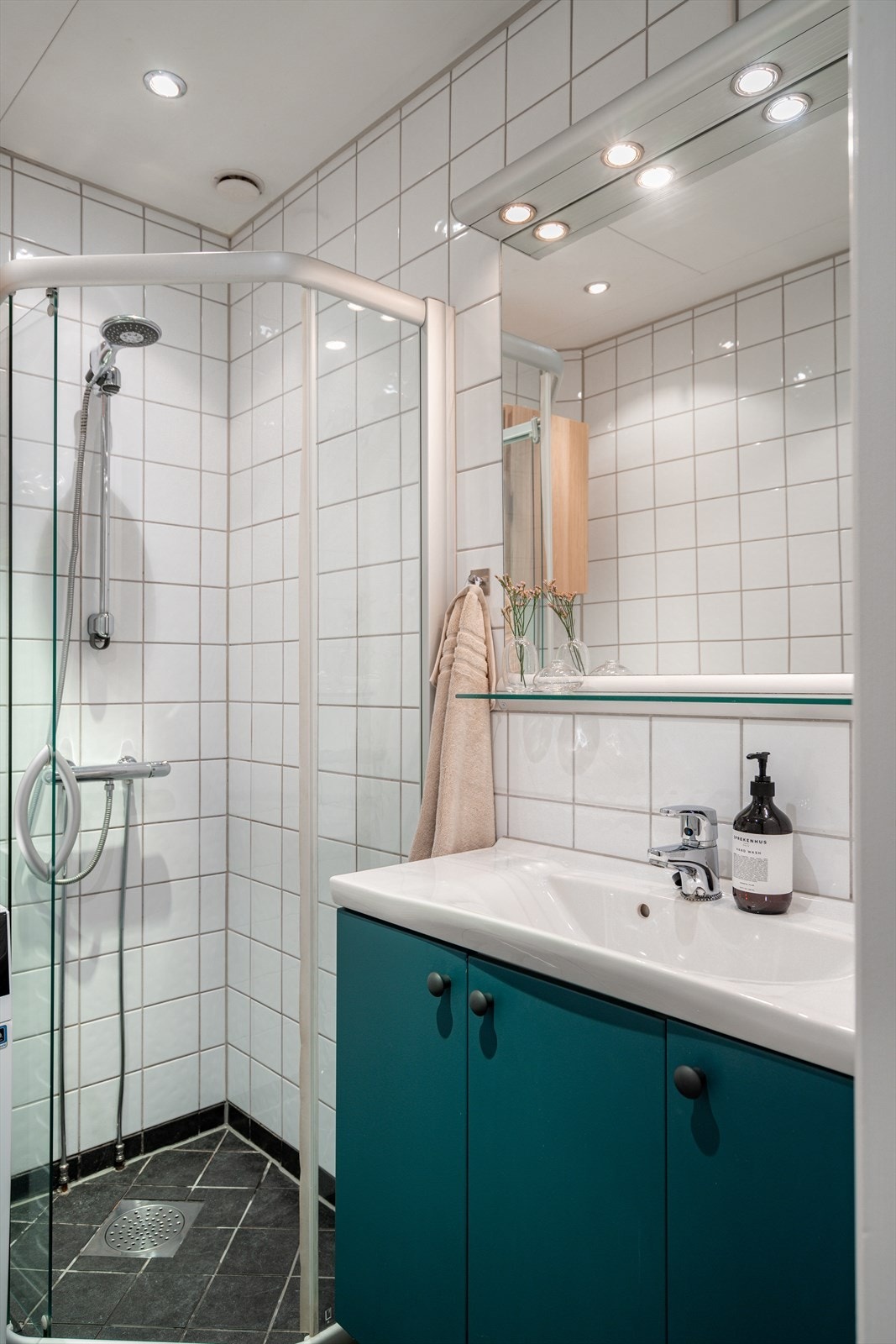 Badet er innredet med servant med skapinnredning, speil med belysning, veggmonterte dusjvegger og opplegg for vaskemaskin. Galleribilde