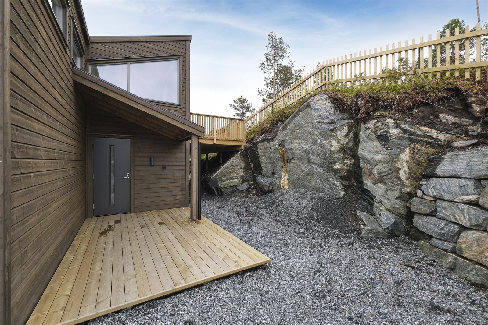 Overbygd inngangsparti med en liten markterrasse i bakkant av hytta. Galleribilde