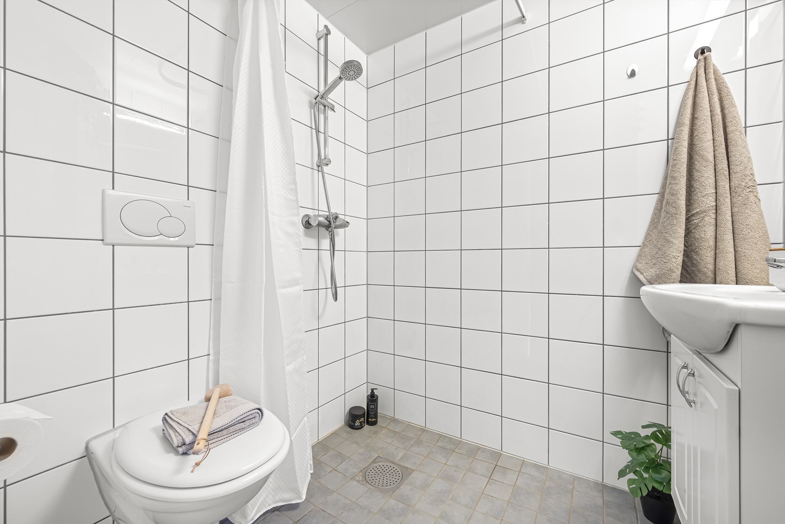 Badet er innredet med vegghengt klosett, innredning med servant, innfelt speil med lys og dusjhjørne. Galleribilde
