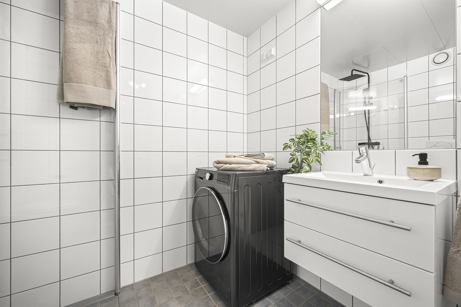 Badet er innredet med vegghengt klosett, servant nedfelt i innredning, innfeltspeil m/lys og dusjhjørne med svingbare glassdører. Galleribilde