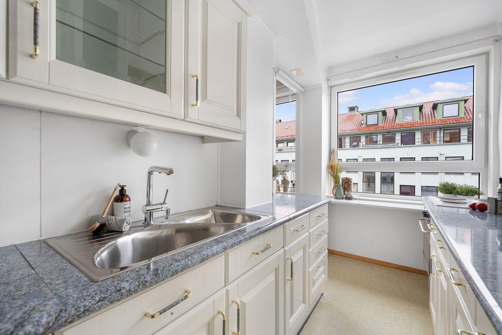 Kjøkkenet består av en klassisk innredning utført med hvite profilerte fronter, noen overskap med glassfronter og benkeplate av laminat. Galleribilde