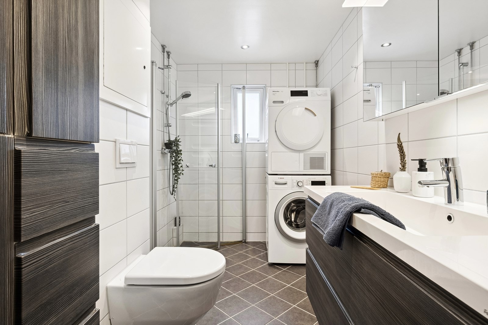 Delikat, flislagt baderom med varmekabler i gulv og downlights i himling. Vaskemaskin og tørketrommel kan medfølge boligen om ønskelig. Galleribilde