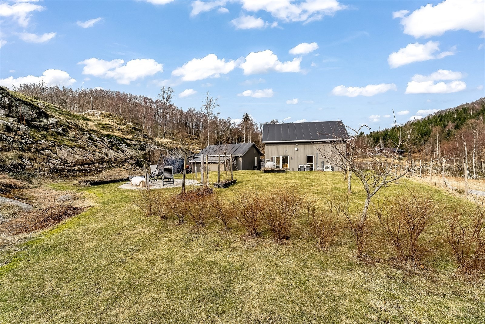 Eiendommen er pent beplantet med plenlagte områder, opparbeidede uteplasser og beplantning. Galleribilde