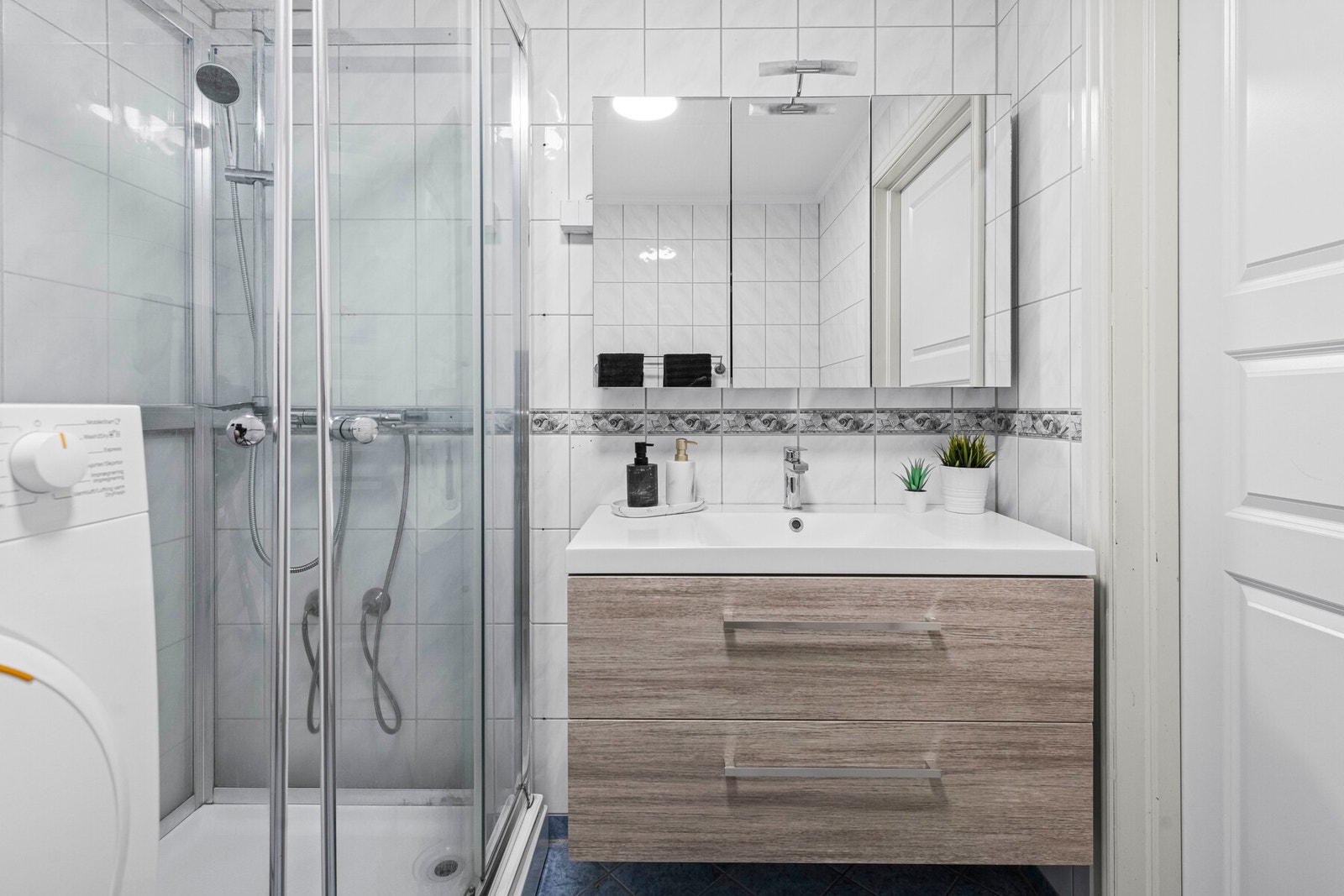 Badet er innredet med servantinnredning, dusjkabinett, opplegg for vaskemaskin samt wc. Galleribilde