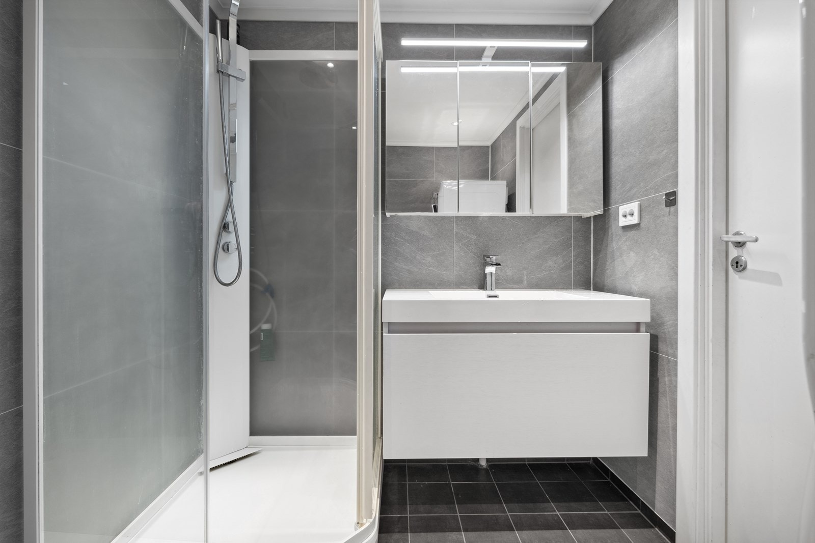 Badet er innredet vegghengt toalett, vask i seksjon, speil, dusjkabinett og opplegg for vaskemaskin og tørketrommel. Galleribilde