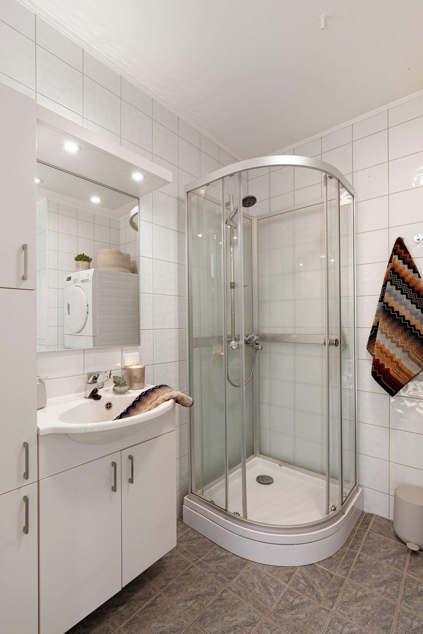 Flislagt bad med dusjkabinett, wc og baderomsinnredning med oppbevaringsplass. Galleribilde