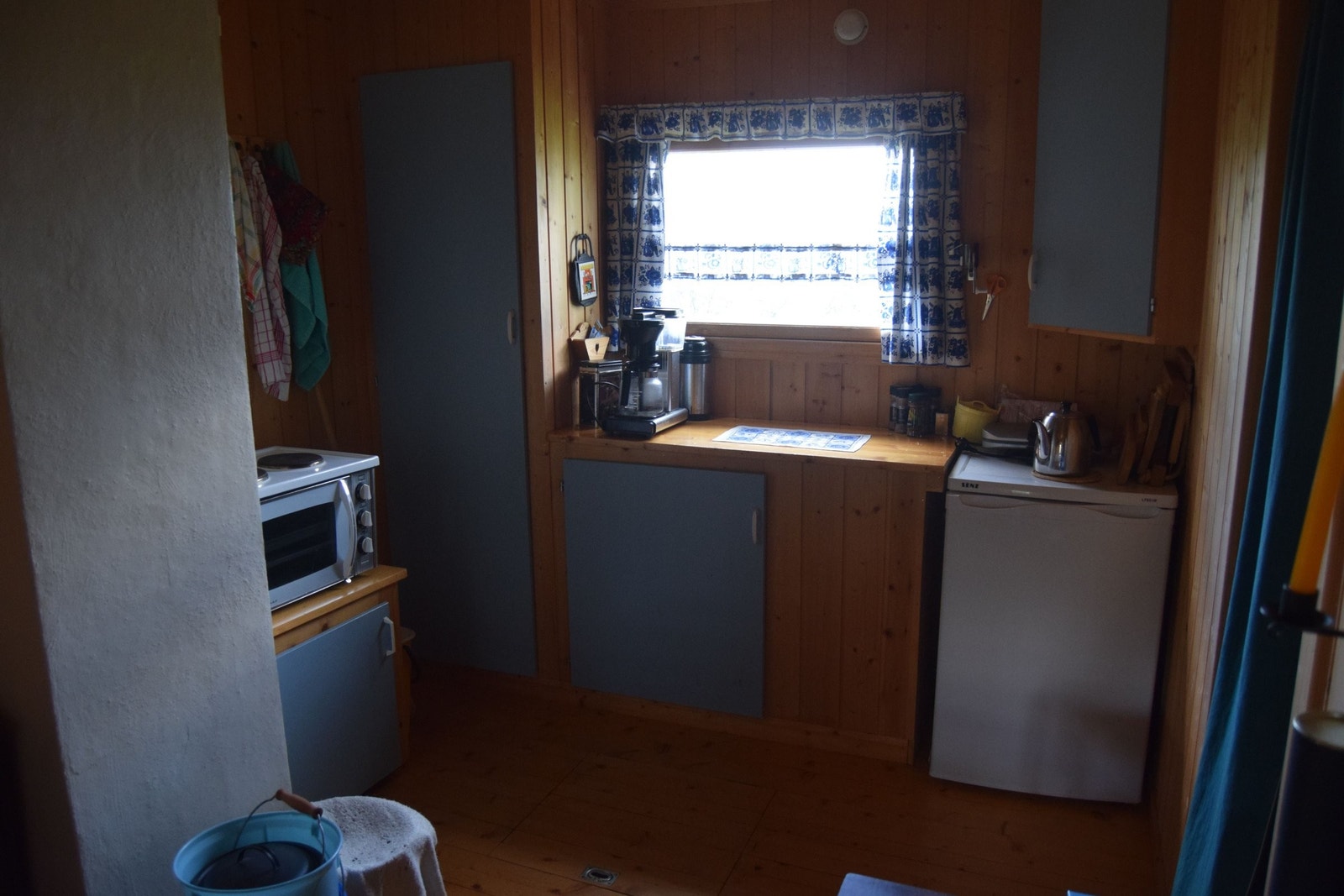 Kjøkkenkrok med enkel, plassbygd kjøkkeninnredning, greie koke- og steikemuligheter og nytt kjøleskap med fryseboks. Galleribilde