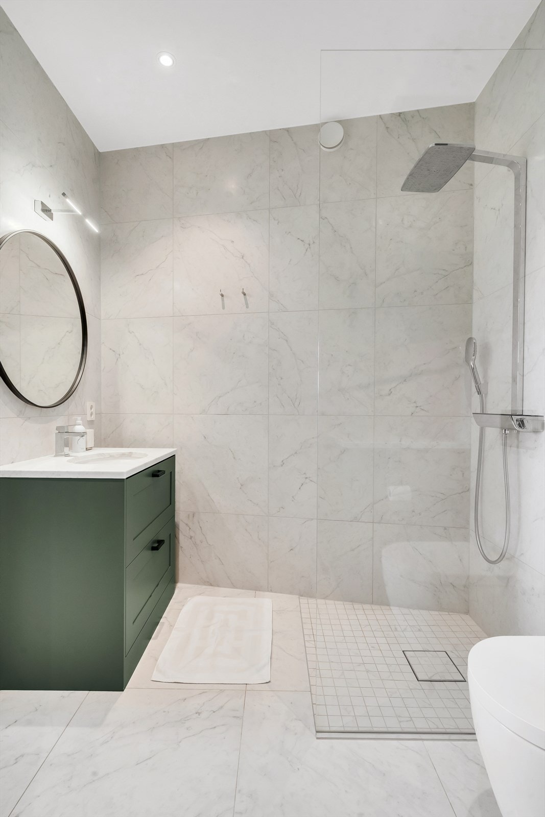 En suite tilknyttet soverom 2 har vegghengt wc, marmor benkeplate med underlimt servant med skap under og dusj i hjørne med glassvegg Galleribilde