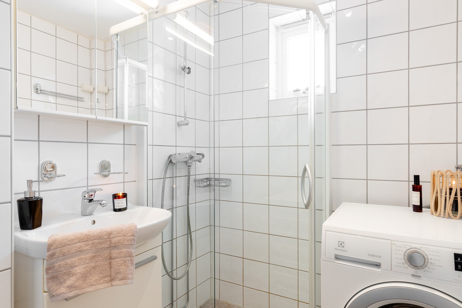 Badet er utstyrt med innredning med nedfelt servant, speil med lys over, veggmontert toalett og dusjvegger/hjørne. Galleribilde