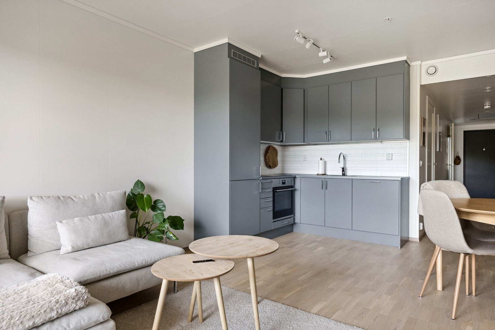 Vinklet kjøkkeninnredning med grå, glatte fronter. Integrert kjøle-/fryseskap, oppvaskmaskin og komfyr med steketopp. Galleribilde