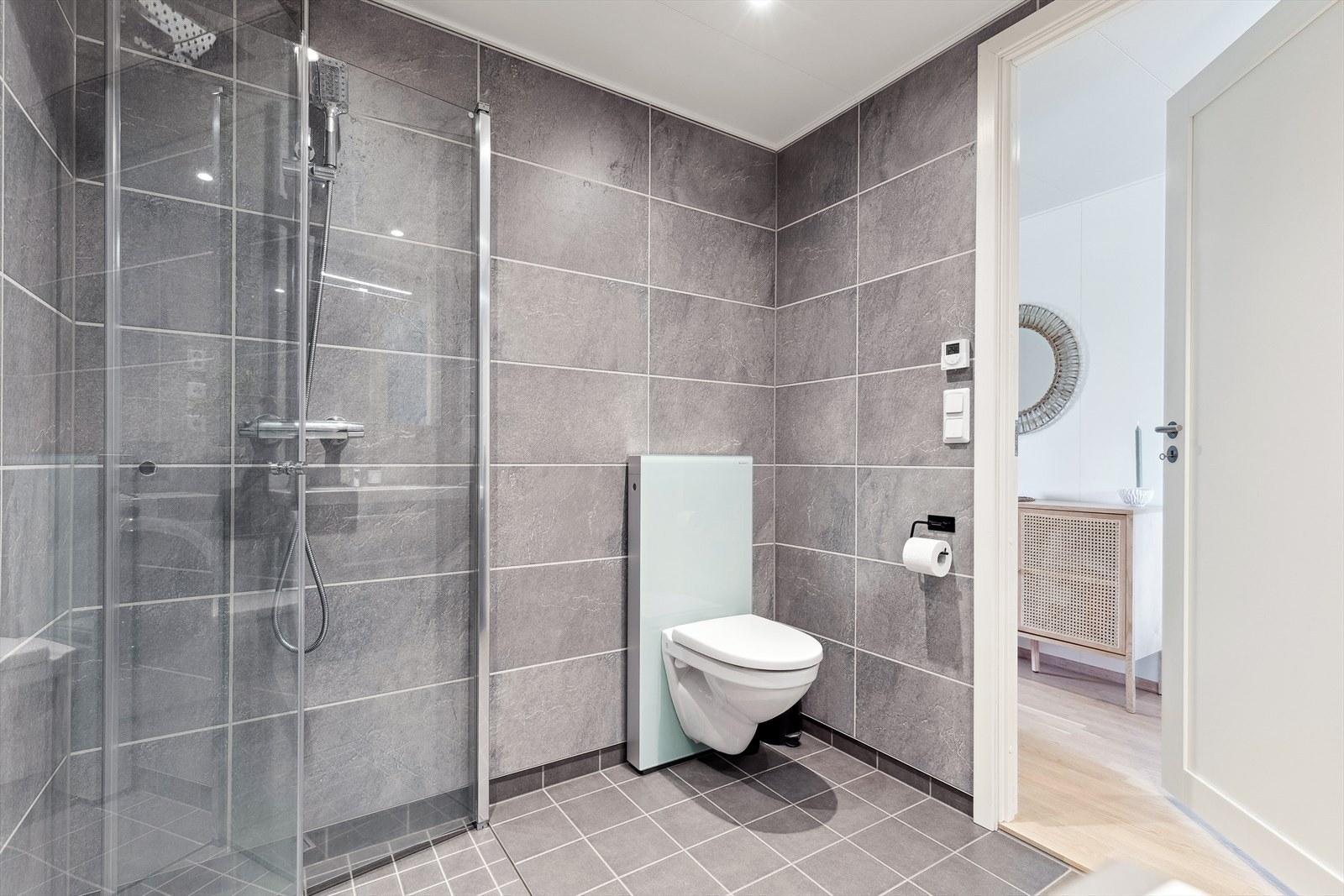 Nøytralt bad med flislagt gulv med varmekabler og veggflater med baderomsplater. Galleribilde