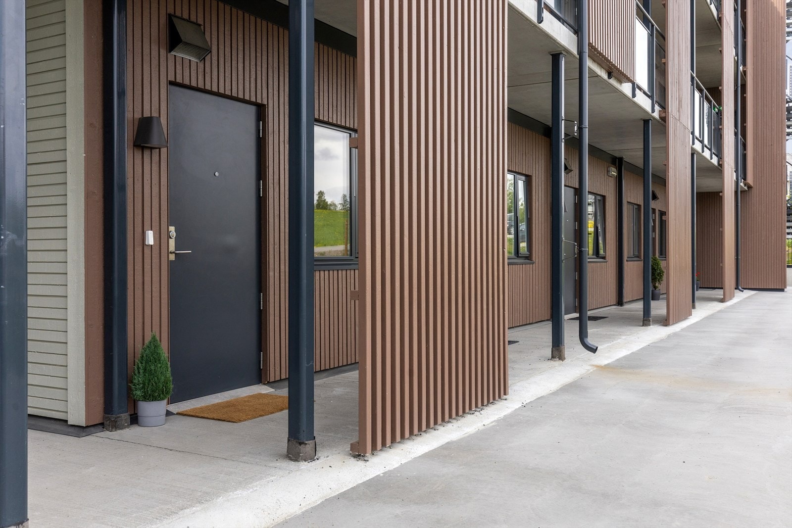 Overbygget inngangsparti tar deg inn til den lyse gangen med praktisk, flislagt gulv. Galleribilde