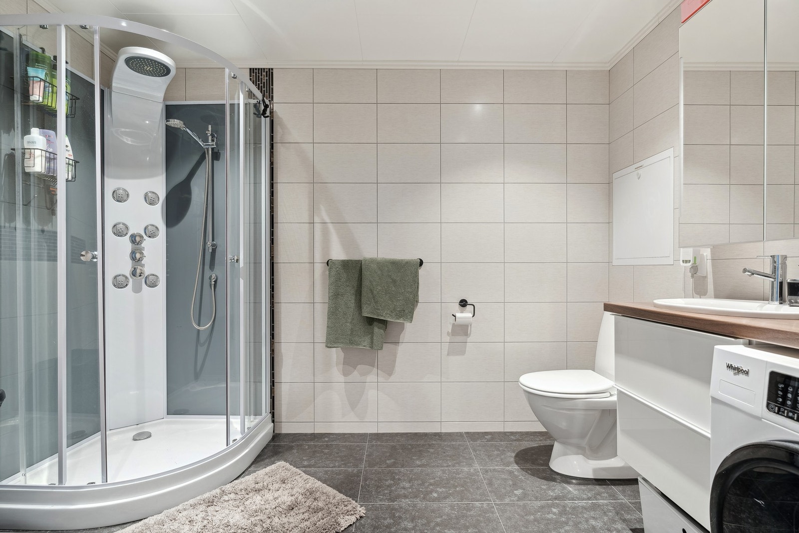 Badet er utstyrt med baderomsinnredning, dusjkabinett, toalett og opplegg for vaskemaskin Galleribilde