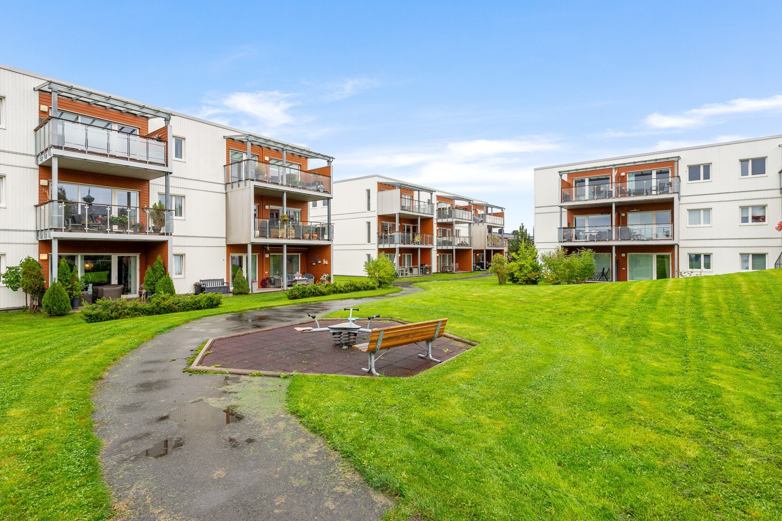 Grøntområdet inneholder lekeapparater for barn, sandkasse og flere benker. Galleribilde