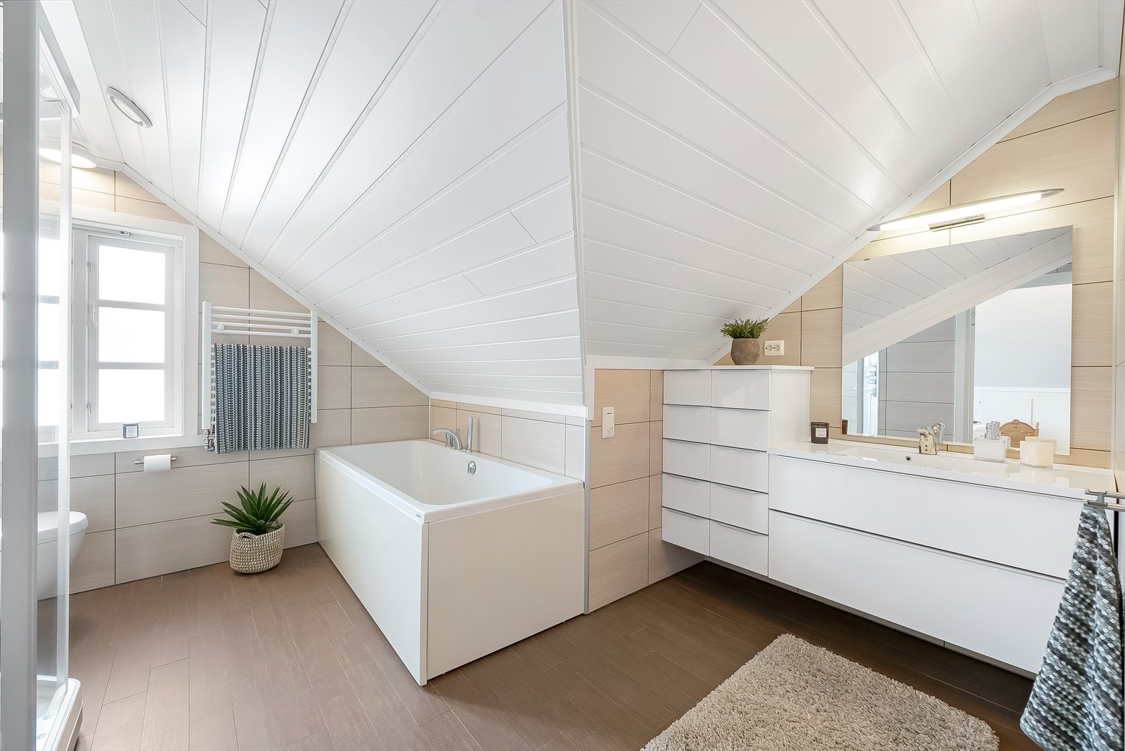 Pent og tidløst innredet bad på loftet. Her er det innredet med baderomsinnredning. toalett, dusjkabinett og badekar. Galleribilde