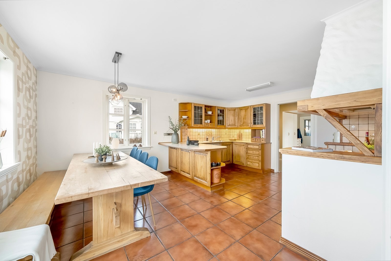 Pent kjøkken i heltre gummitre med integrerte hvitevarer og forlenget benkeplate mot spiseplassen. Galleribilde