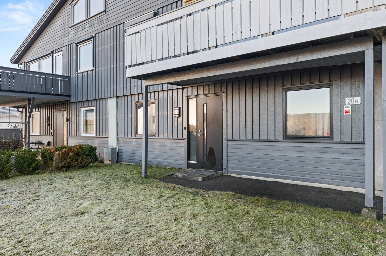 På fremsiden er det plen med beplantning og asfaltert gårdsplass Galleribilde