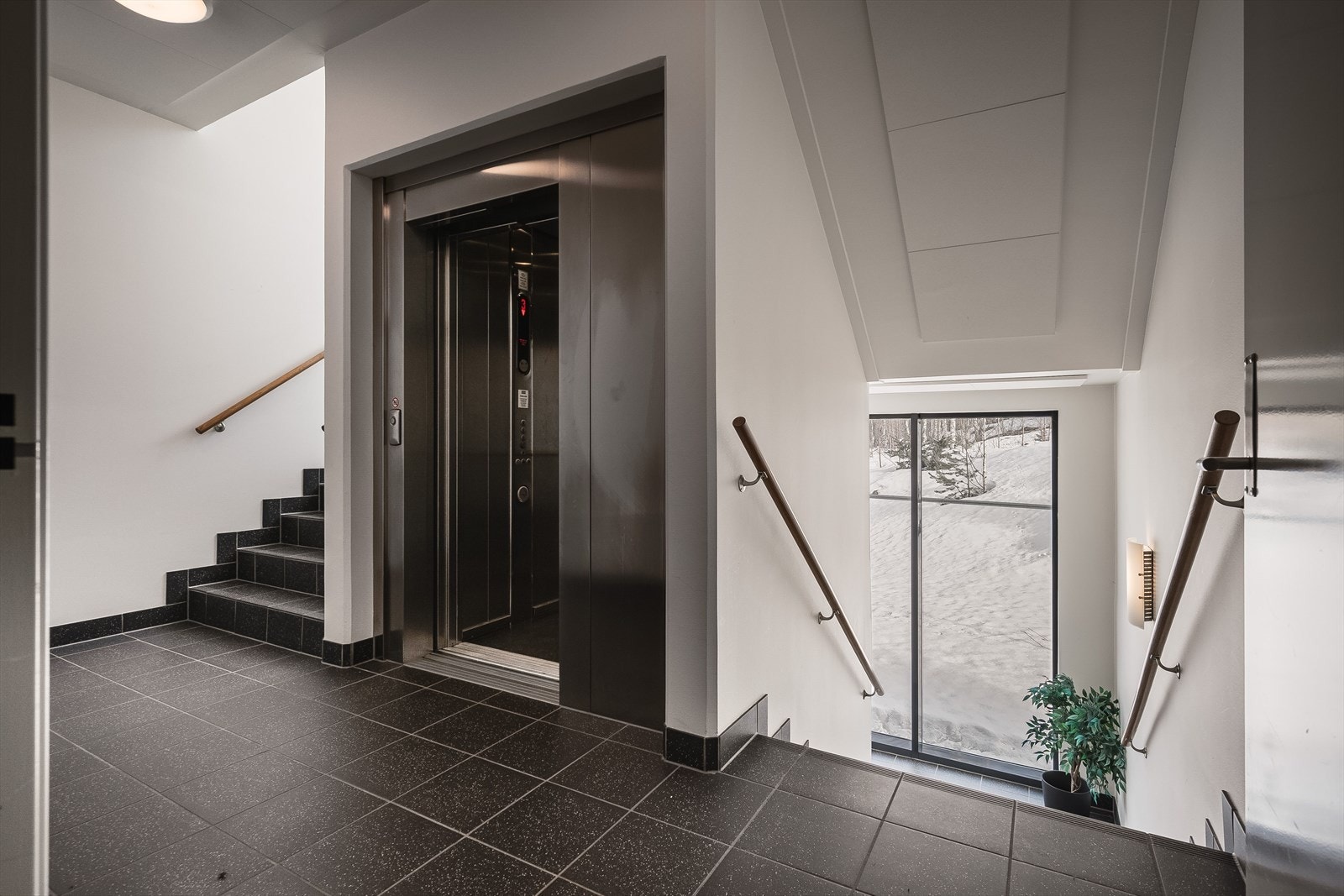 Felles trappegang med heis. På halvplan mellom 3. og 2. etasje er det utgangsdør til fellesområdet mot skogen. Galleribilde