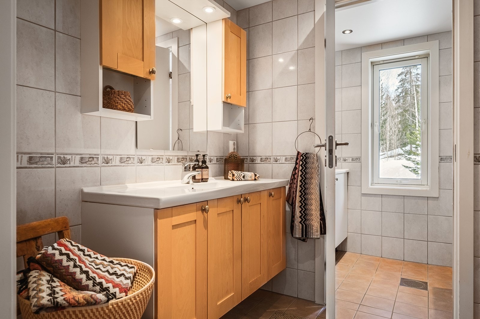 Badet i leiligheten har god plassering og adkomost til et praktisk og separat vaskerom. Badet er varmekabler i gulv og downlights i tak. Innrendingen med heldekkende servant over udnerskap med rette profilfronter. Egen dusjnisje, samt vegghengt wc. Galleribilde