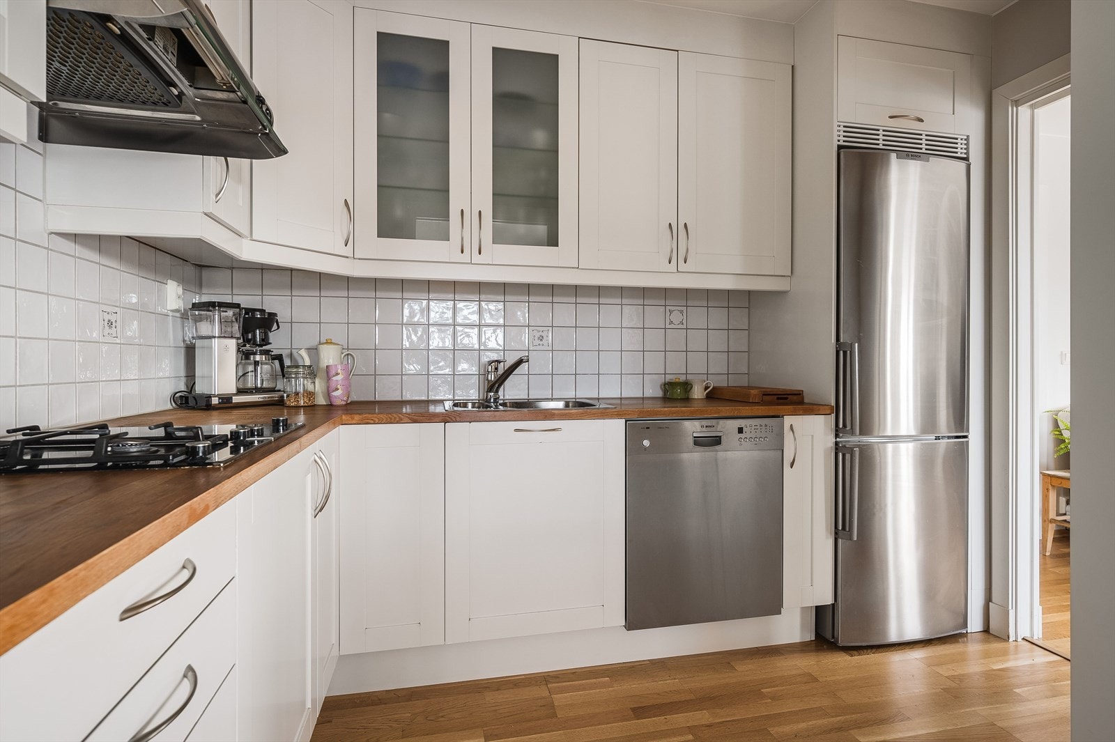 Kjøkkenet er godt plassert i leiligheten og har adkomst fra både stue- og spisestuedel. Innredningen har en lys og fin fremtoning med rette profilfronter og takhøye overskap. Ett overskap med glass. Egen nisje til kjøl-/fryseskap. Galleribilde