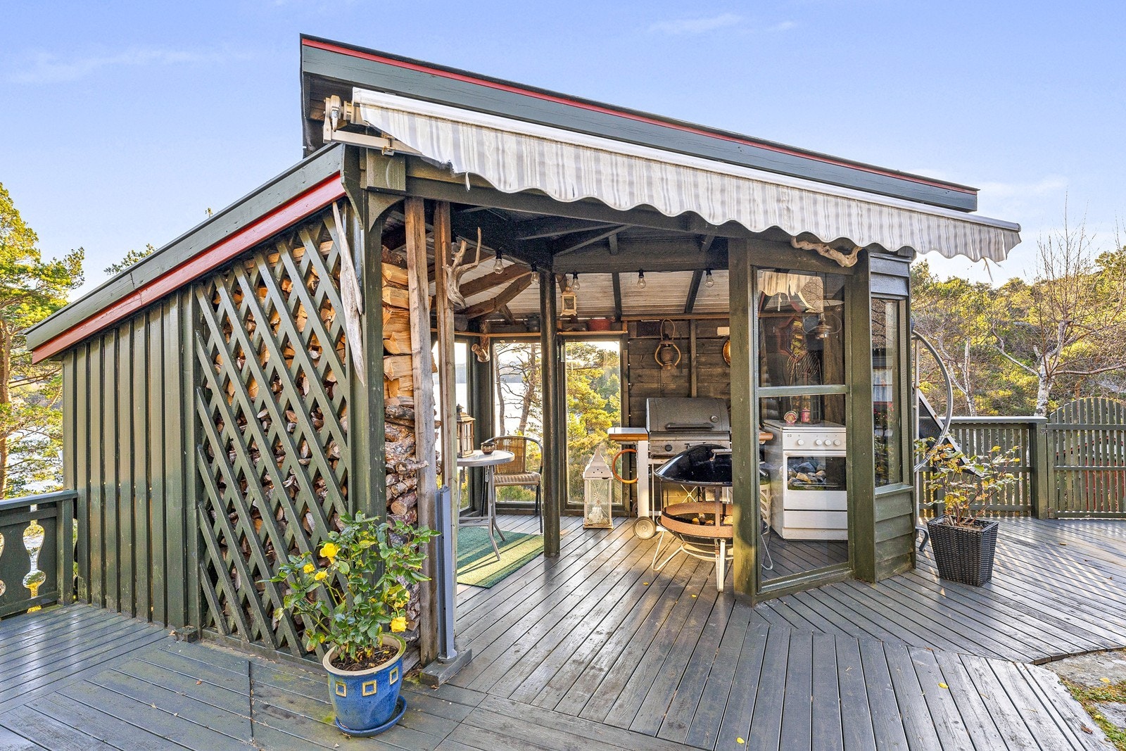 Hagestue med store vinduer mot sjø og god plass til hagemøbler. Galleribilde