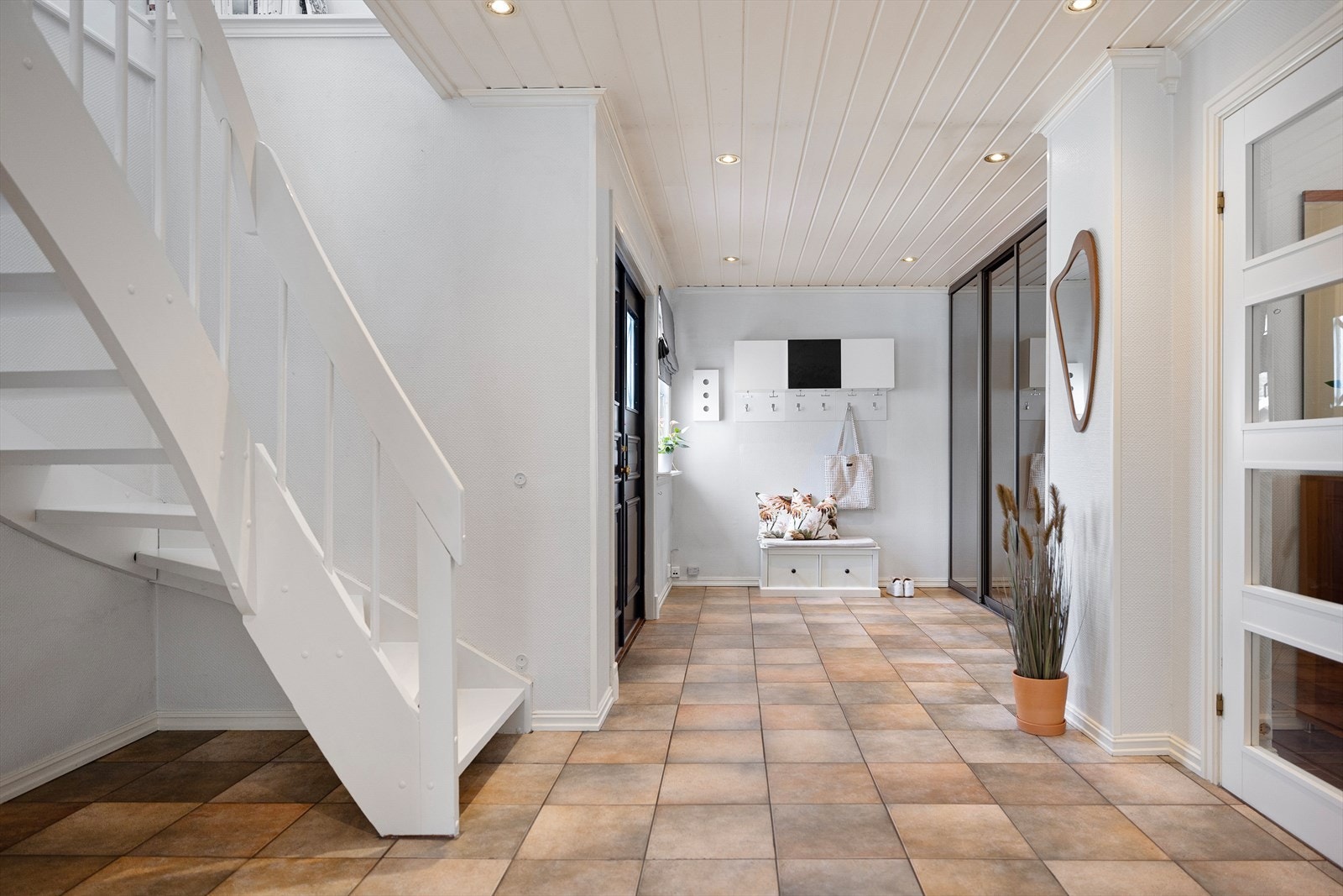 I entreen møter vi er et stort og lyst rom - med lune fliser på gulvene, pen klassisk belistning, hvitmalt panel og downlights i taket. Galleribilde