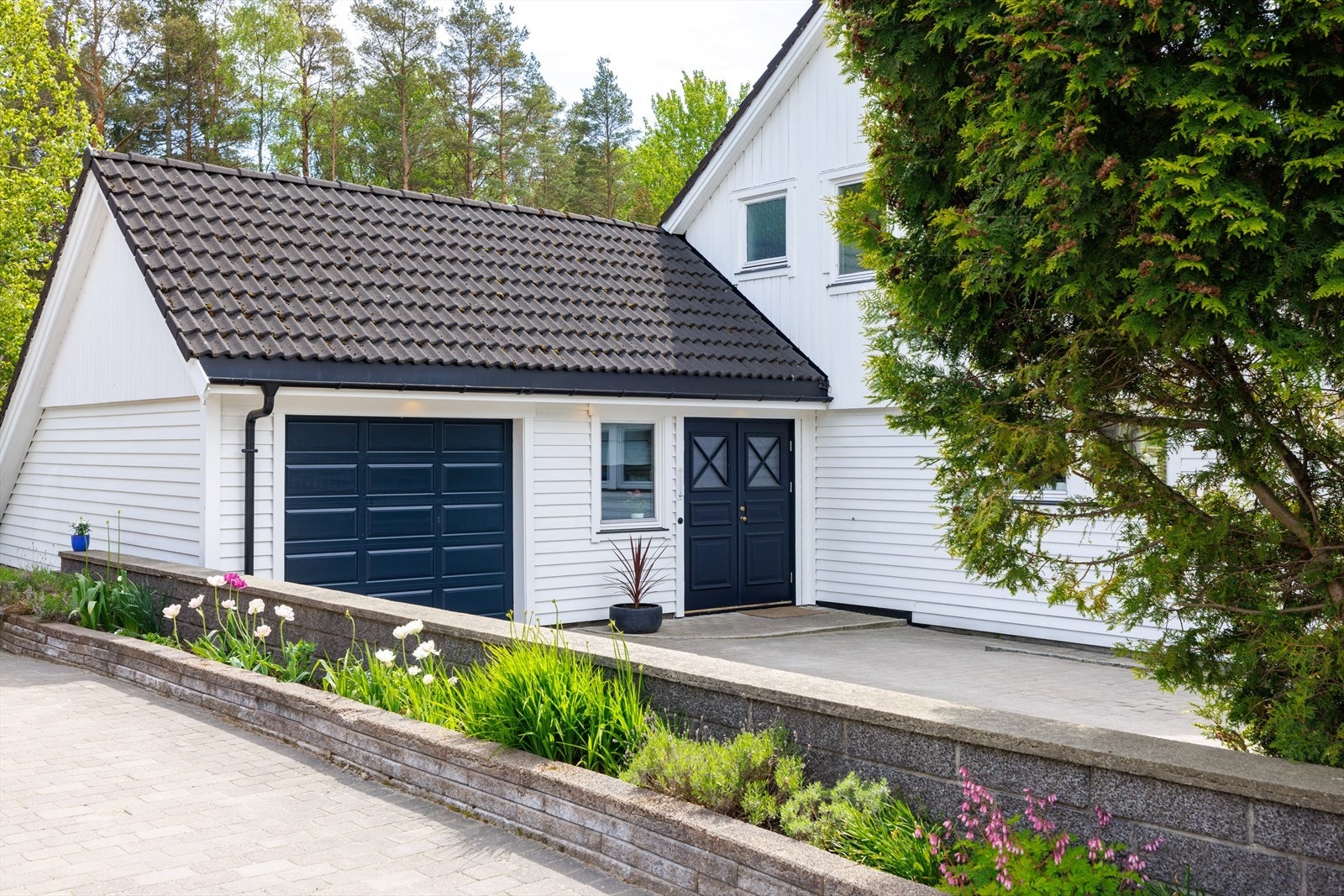Boligen fra 1986 ligger nesten innerst i den lite trafikkerte Tapperiveien. En veltrimmet hekk løper rundt huset, bortsett fra den pent steinlagte gårdsplassen inn mot garasjen der en mur avgrenser mot naboen. Galleribilde