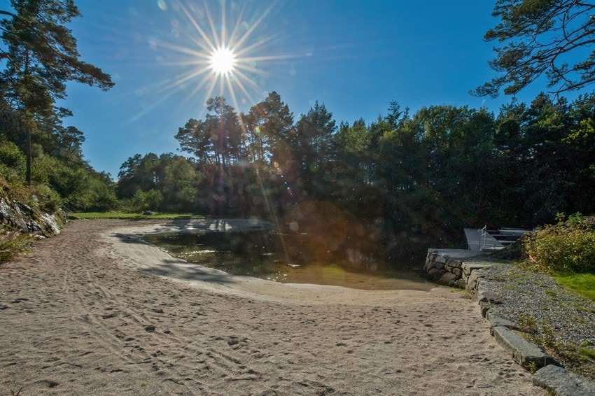 Nydelig felles sandstrand i solrike omgivelser. Galleribilde