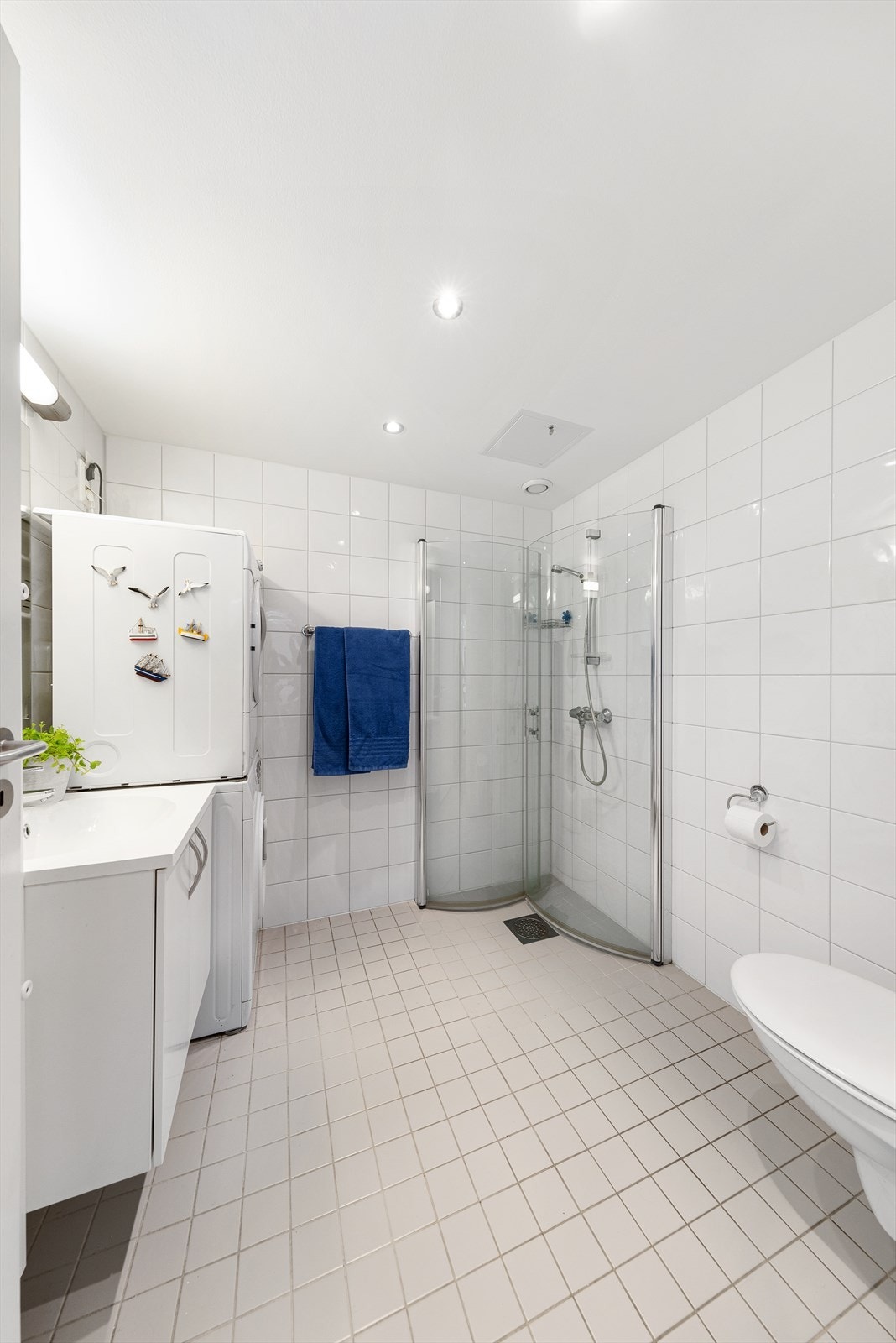 Badet er flislagt med varmekabler i gulv og inneholder wc, servant med underskap og speil, dusjhjørne og opplegg til vaskemaskin. Galleribilde