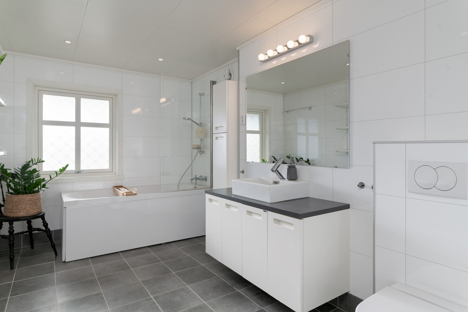 Badet har servant på innredning, badekar med dusjnisje og veggmontert toalett. Galleribilde