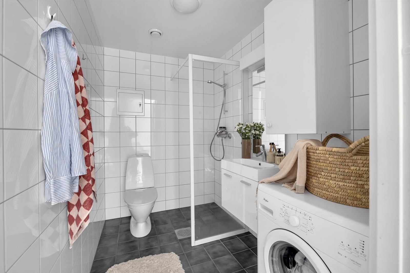Badet er flislagt og har gulvvarme. Uttak til vaskemaskin. Oppbevaring i skap og underskap med heldekkende servant. Galleribilde