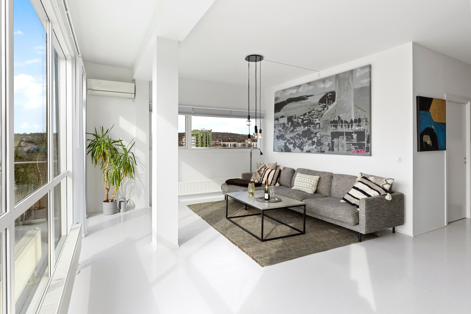 Stuen har malte parkettgulv mot lyse veggflater med listefrie overganger til himling, noe som gir et stilrent uttrykk. Galleribilde