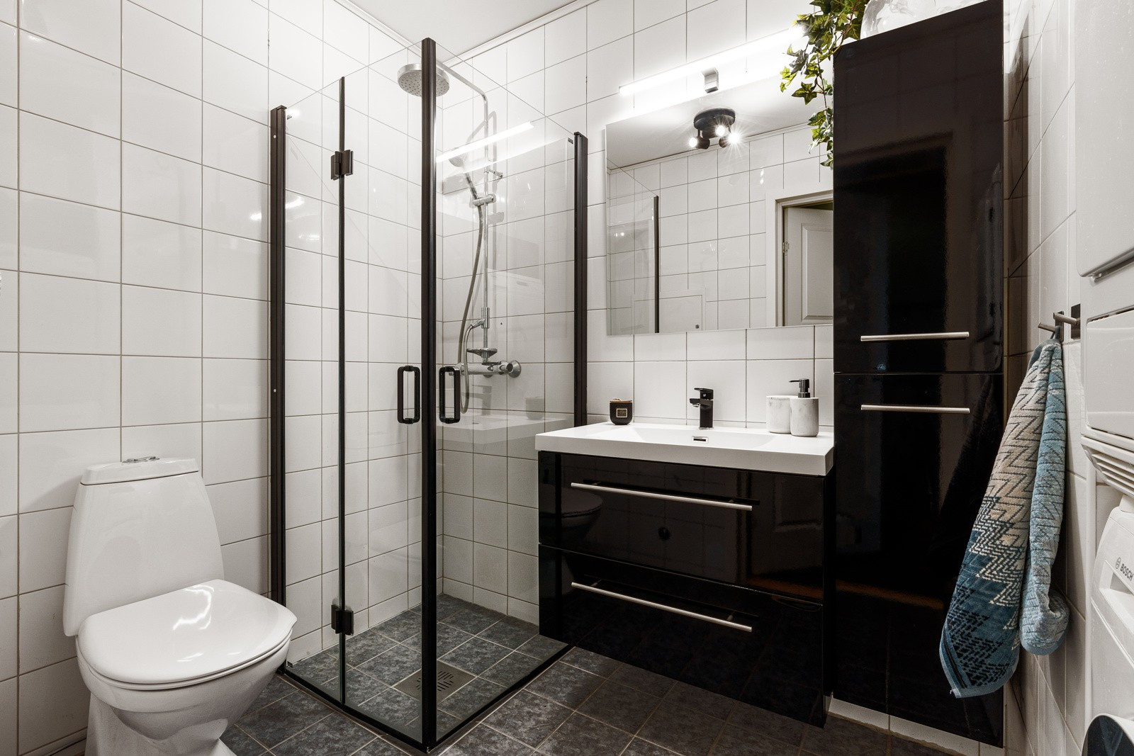 Flislagt bad som er utstyrt med romslig dusjhjørne, wc og baderomsinnredning med god oppbevaringsplass. Både innredningen og dusjdørene er skiftet.