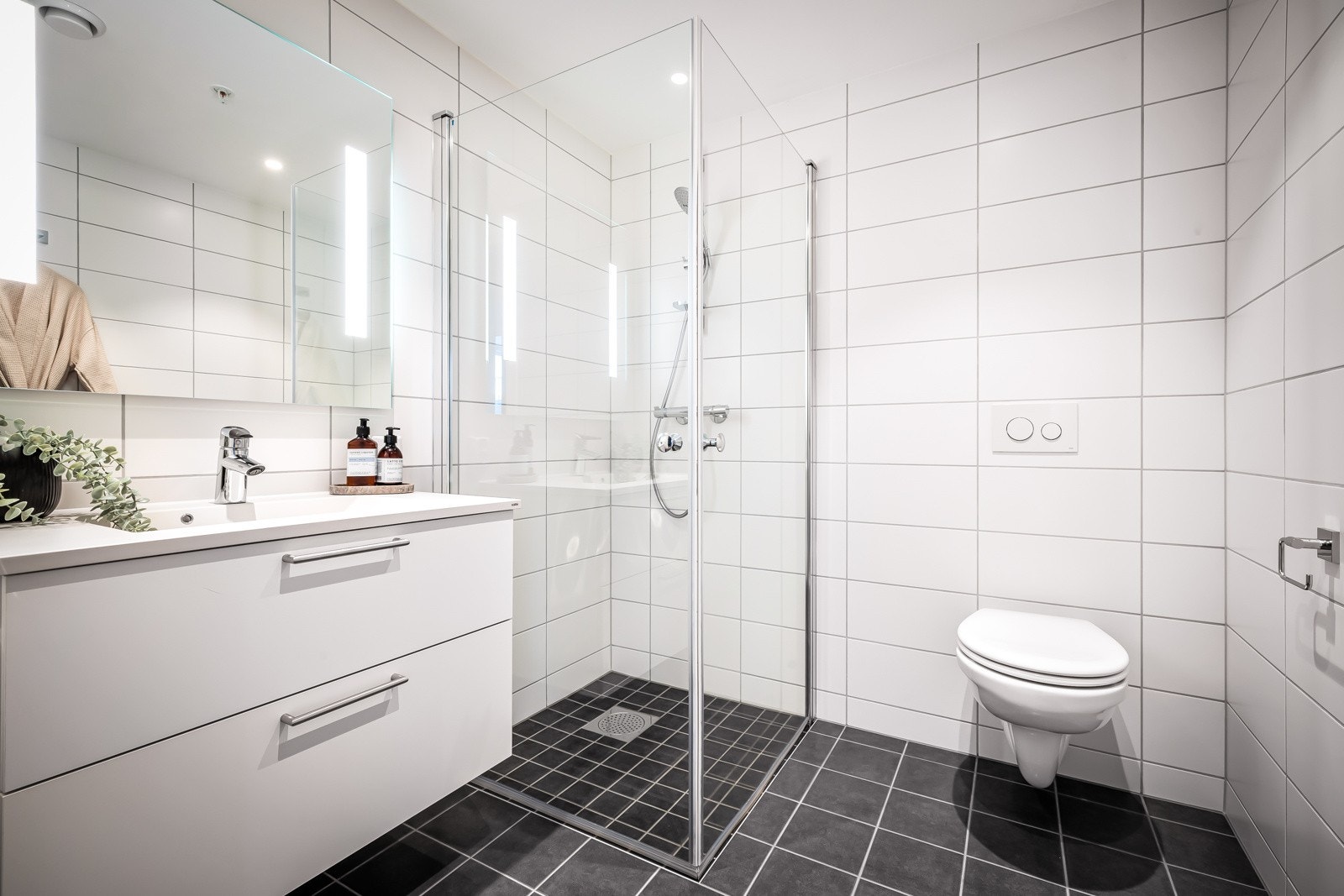 - Begge bad er flislagt i en stilren kombinasjon av mørkegrått og hvitt - Galleribilde