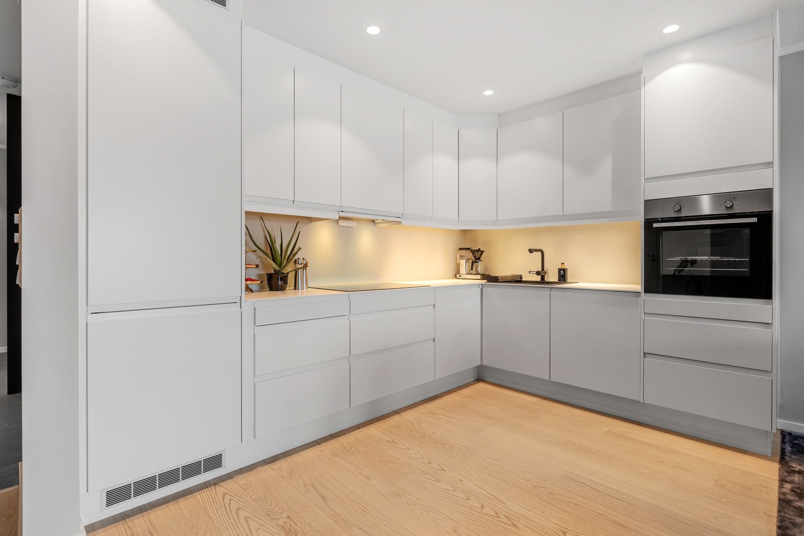 Innredning med hvite fronter, innebygde hvitevarer og med laminert benkeplate. Galleribilde