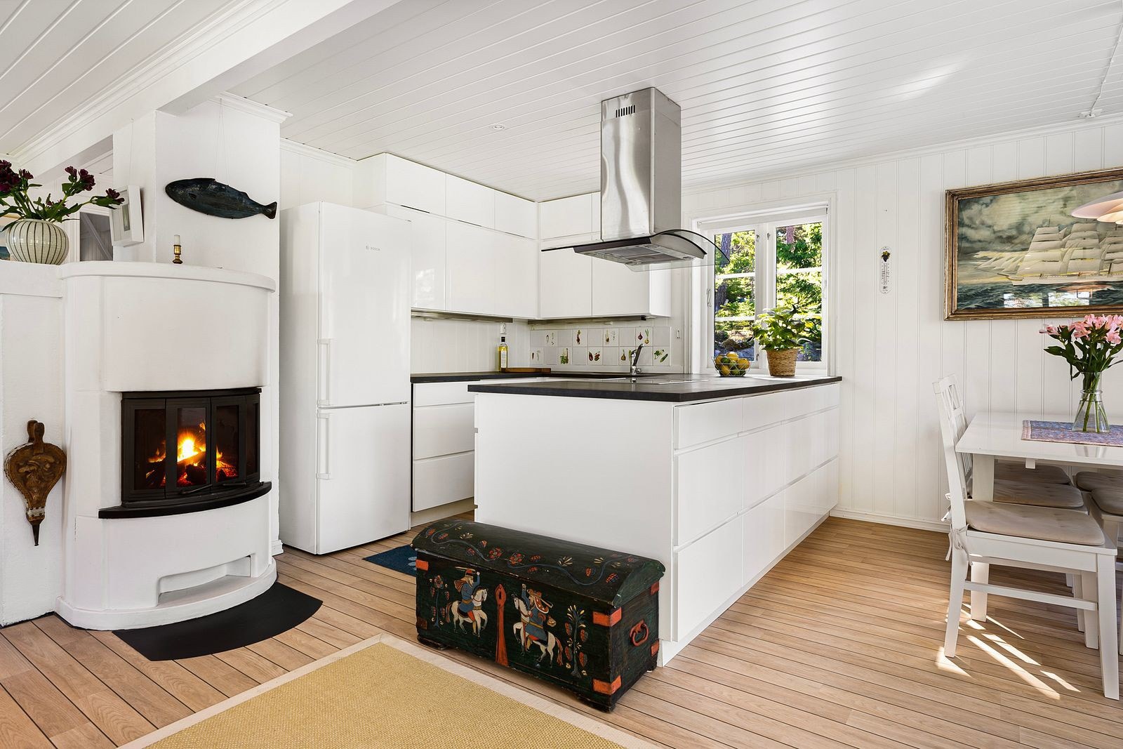 Kjøkkeninnredningen er tidsriktig og har glatte fronter, laminat benkeplate med planlimt stålkum og fliser over benken. Galleribilde