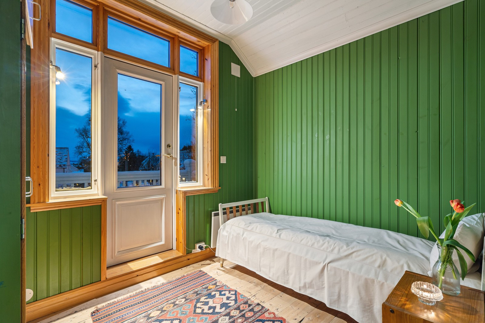 Boligens 2. soverom er malt i en fresh grønnfarge og har egen sørvendt veranda. Flott plass å nyte formiddagskoppen i rolige omgivelser.
