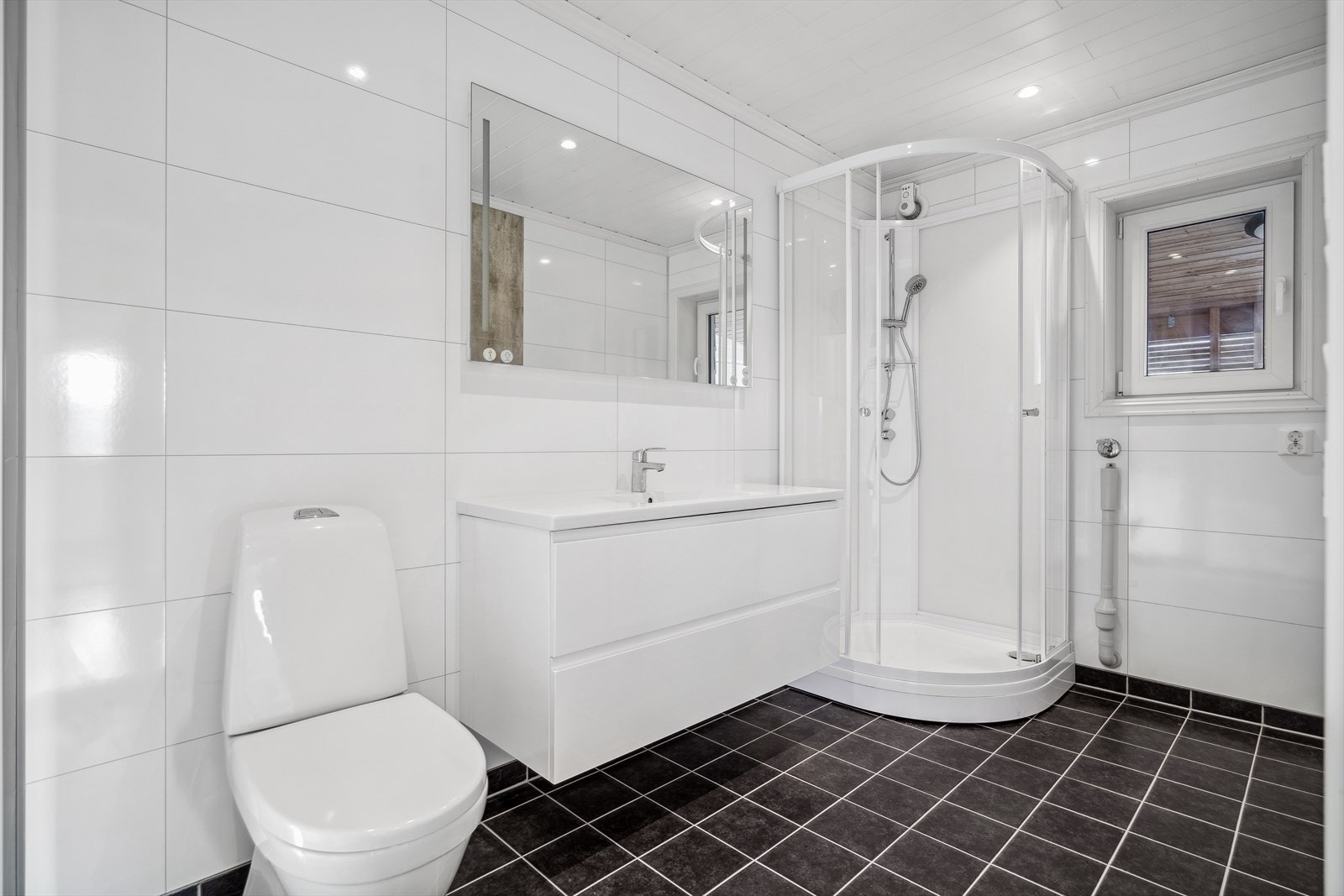 Baderommet er innredet med dusjkabinett, innredning med servant, toalett og opplegg for vaskemaskin. Galleribilde