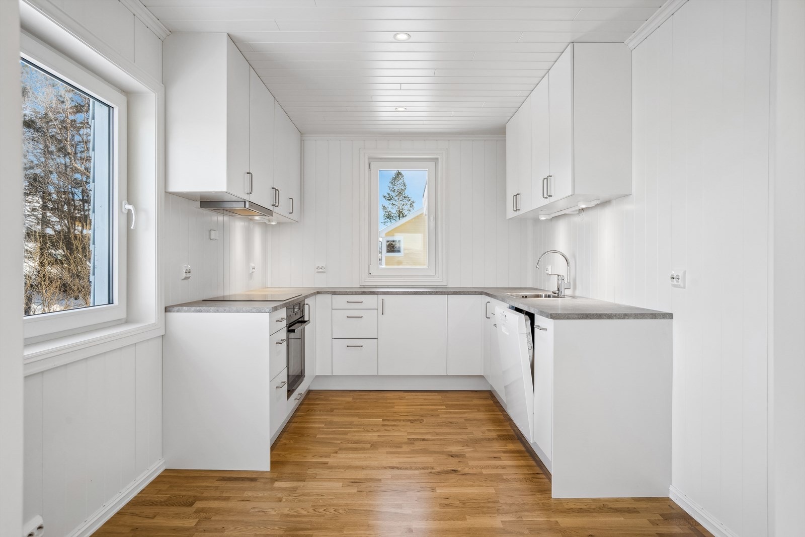 Kjøkkenet har innredning med hvite glatte overflater og laminat benkeplate. Galleribilde