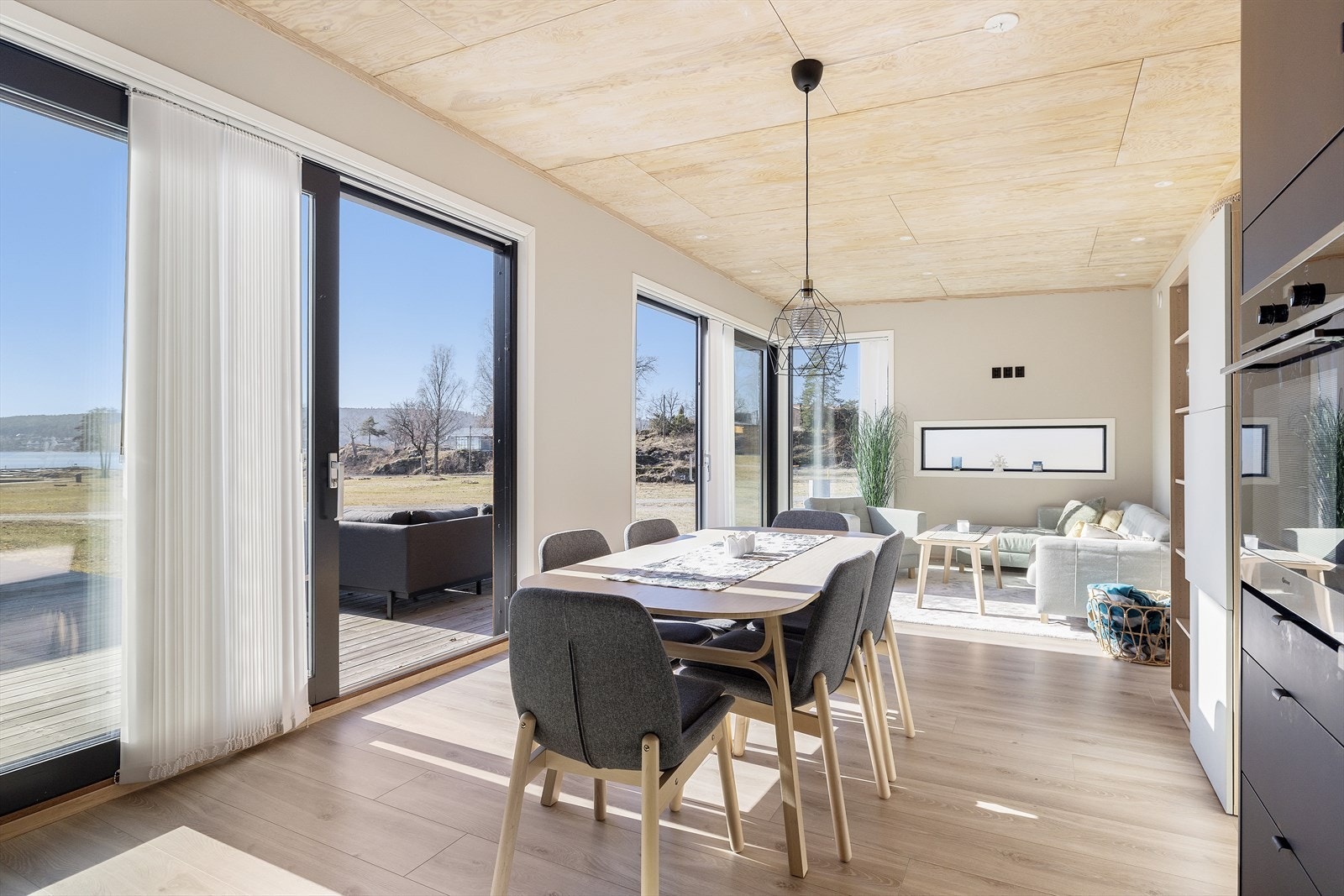 Lys og romslig stue og kjøkken i åpen løsning. De store vindusflatene slipper fint lys inn i rommet Galleribilde