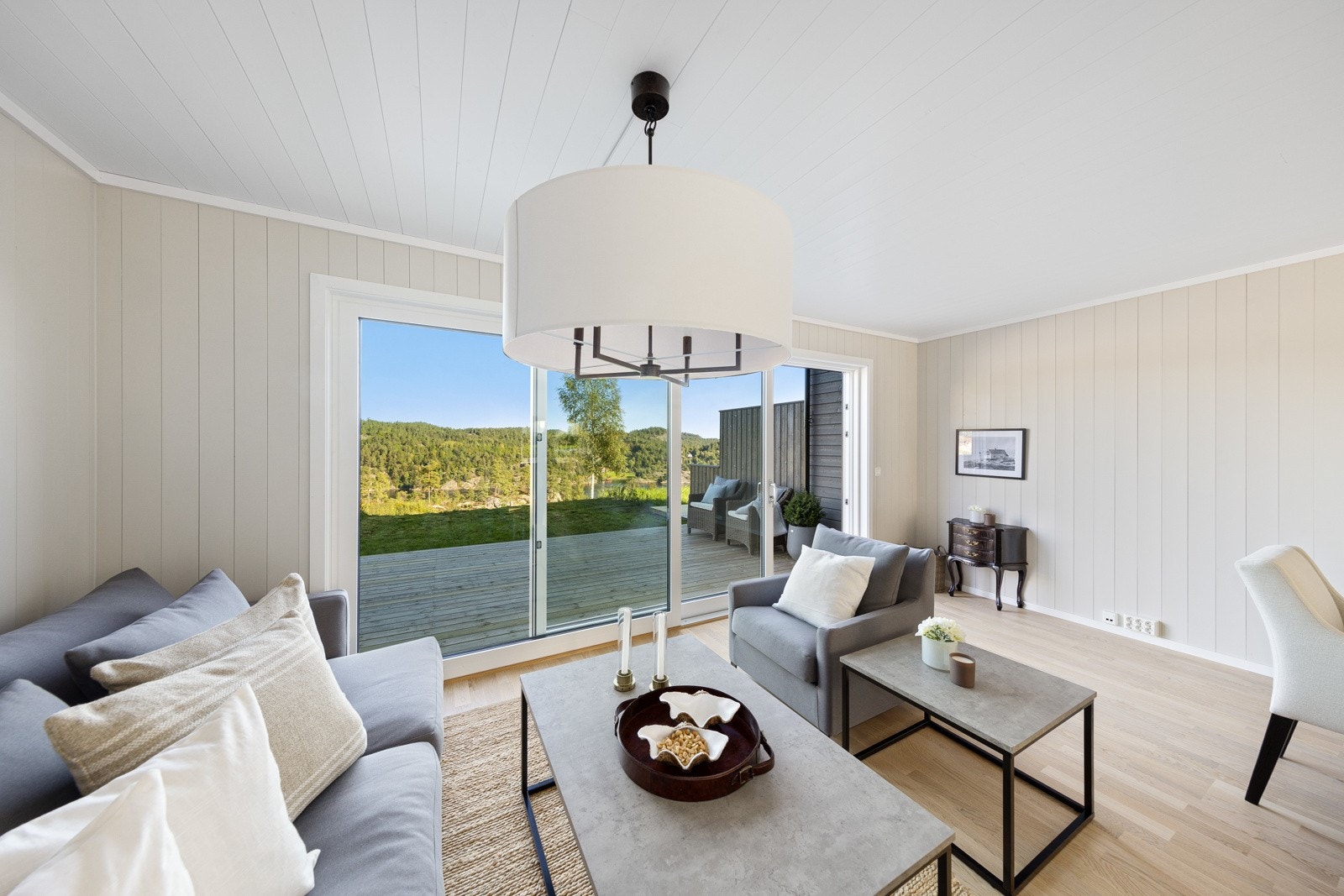 Hytta har en koselig og lys stue med store vindusflater og en skyvedør som trekker uteplassen inn som en del av stuen. Galleribilde