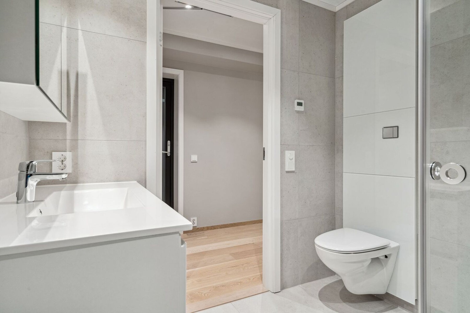 Stilrent bad med speilskap, vegghengt toalett og dusj. Fra bad ser du utgang til en av balkongene. Galleribilde