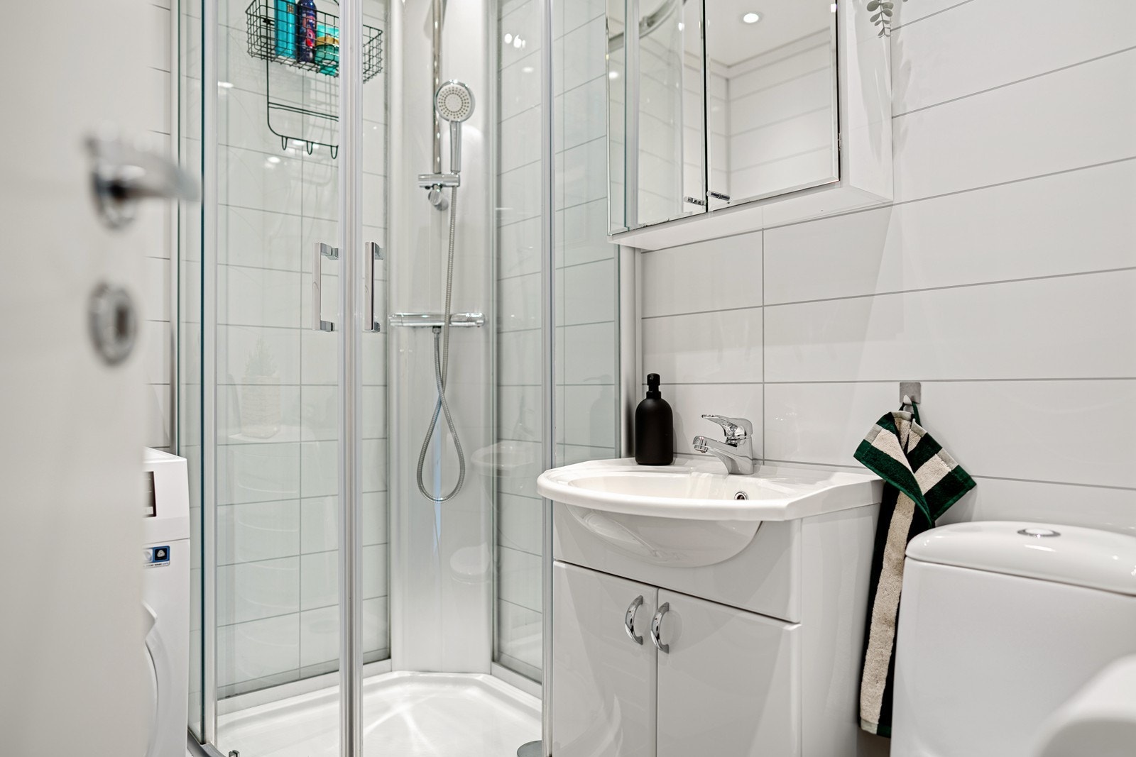 Badet er fint innredet med dusjkabinett, toalett, heldekkende servant i baderomsinnredning og opplegg til vaskemaskin Galleribilde