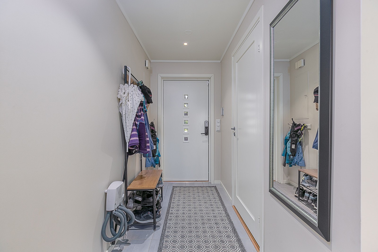 Entrè med fliser på gulvet og dør til toalettrom. Galleribilde