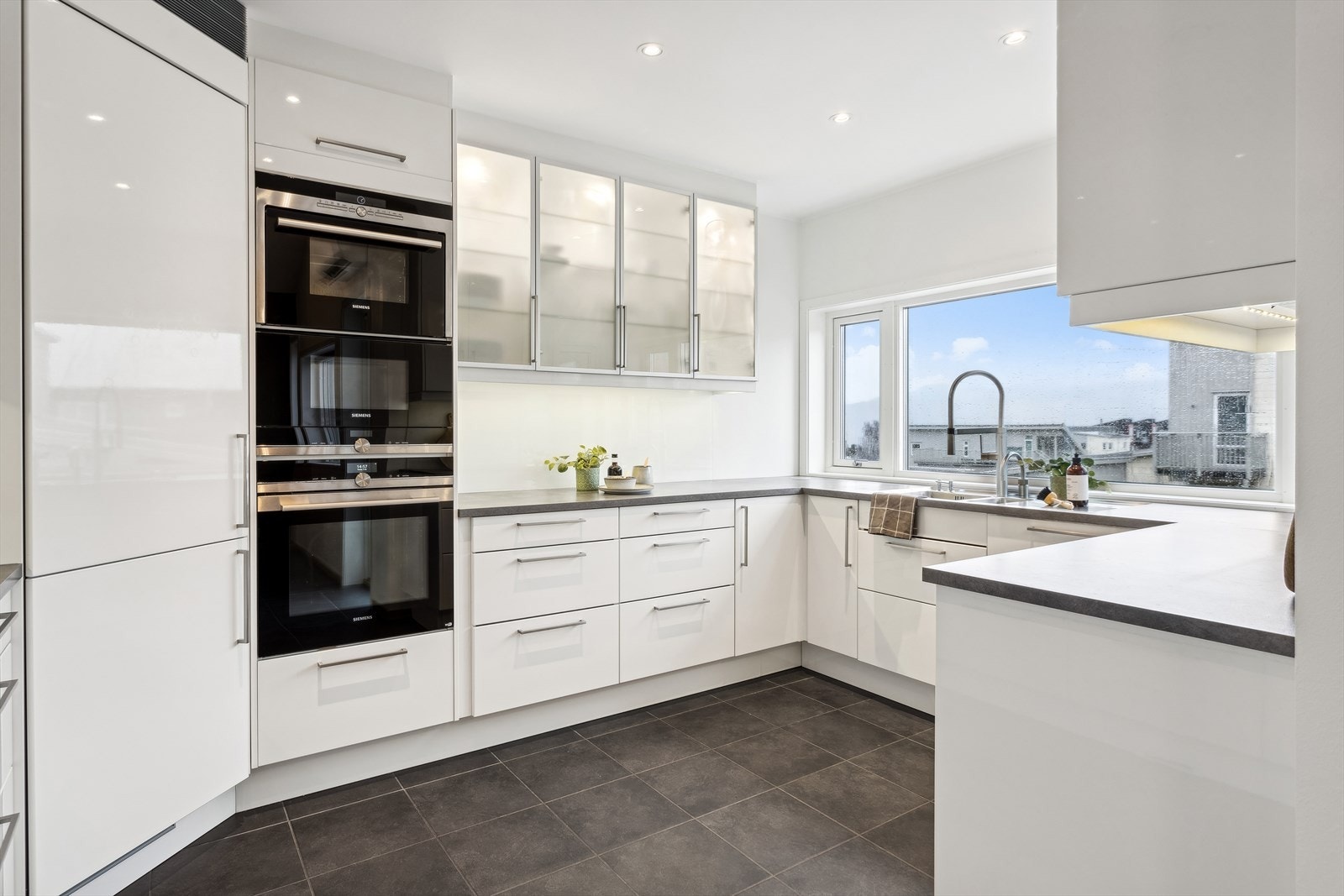 Tidløst kjøkken med hvite høyglans fronter og integrerte hvitevarer. Galleribilde